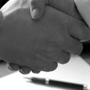 man and woman shaking hands in front of laptop